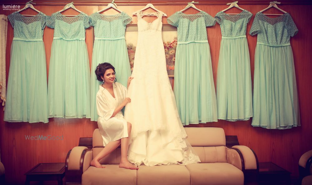 Photo of Bride getting ready with hers and bridesmaids dresses on hanger
