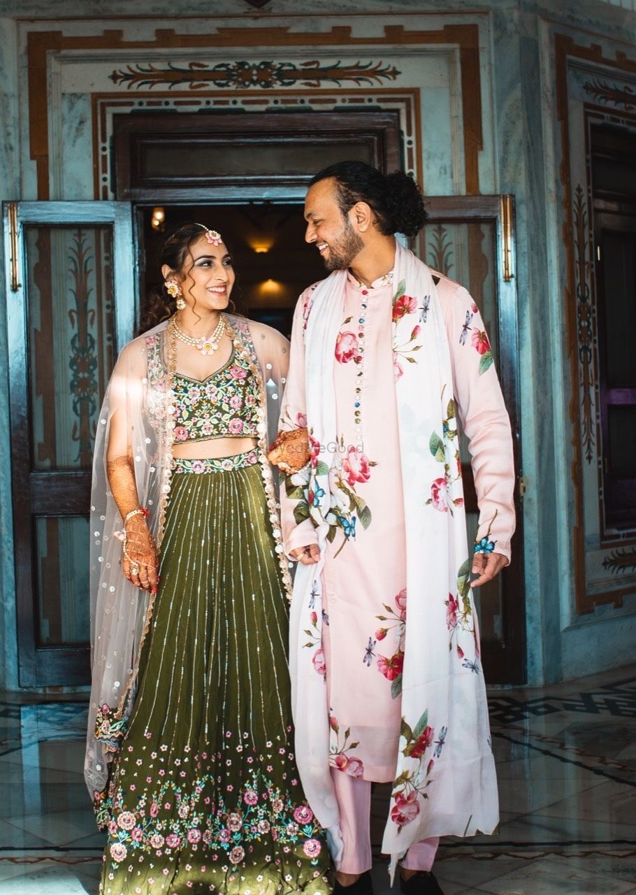 Photo of cute bride and groom mehendi outfits with florals