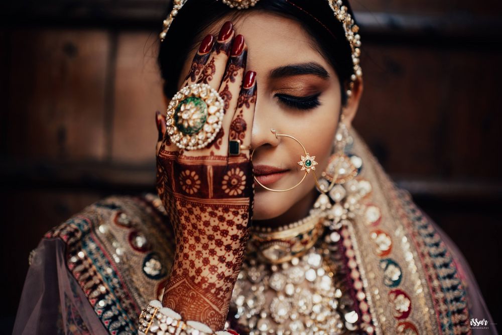 Photo of Bride in traditional jewellery and intricate back hand mehndi design