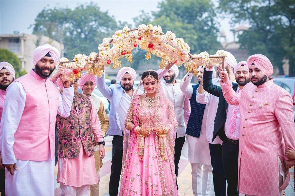 Photo of Sikh bride in light pink entering under unique phoolon ki chadar