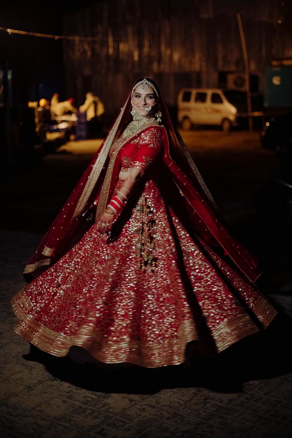 Photo of Bride twirling around in her red and gold lehenga.