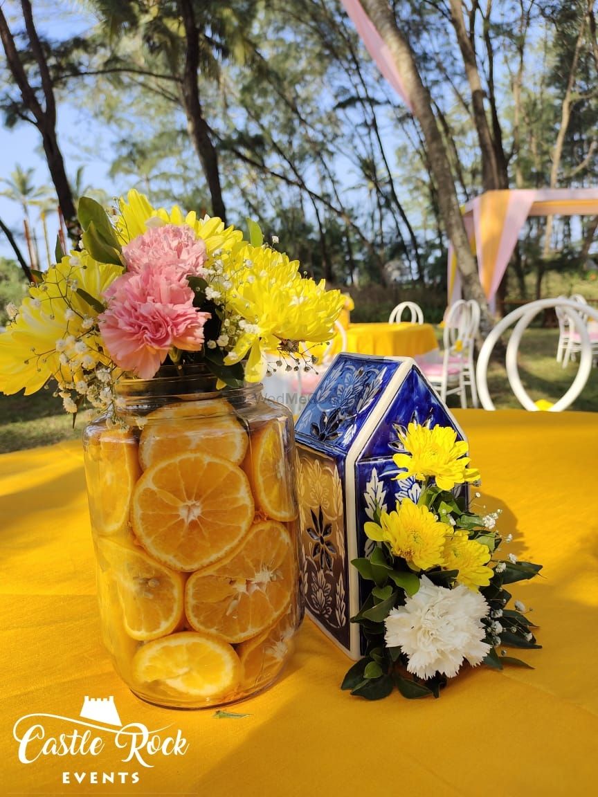 Photo of Mason jars filled with oranges and carnations used as table centrepieces.