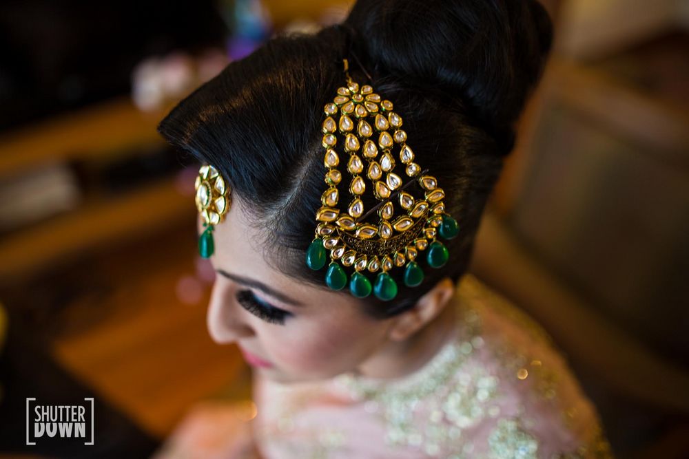 Photo of Bride wearing large jhoomer with green stones