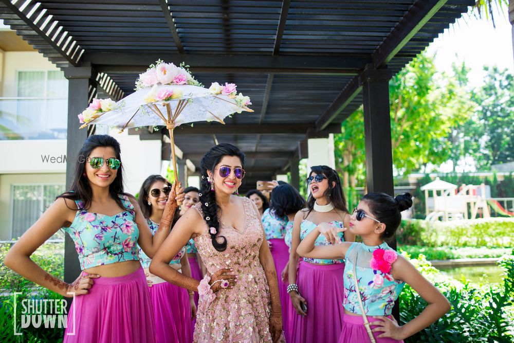 Photo of Bride entering with matching bridesmaids under floral umbrella