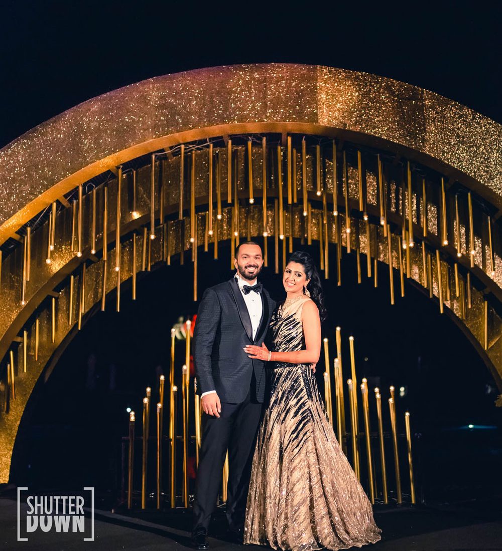 Photo of Glam couple portrait on sangeet with gold decor