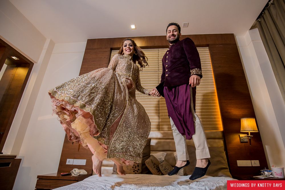 Photo of Fun couple shot with couple jumping on hotel bed