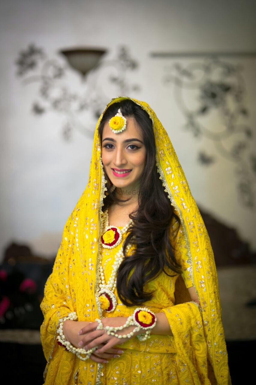 Photo of Bride in yellow wearing pink and yellow floral jewellery
