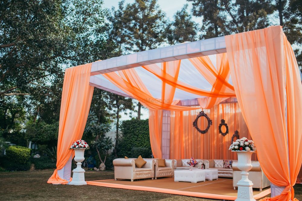 Photo of Orange and white mandap decor with drapes for destination wedding