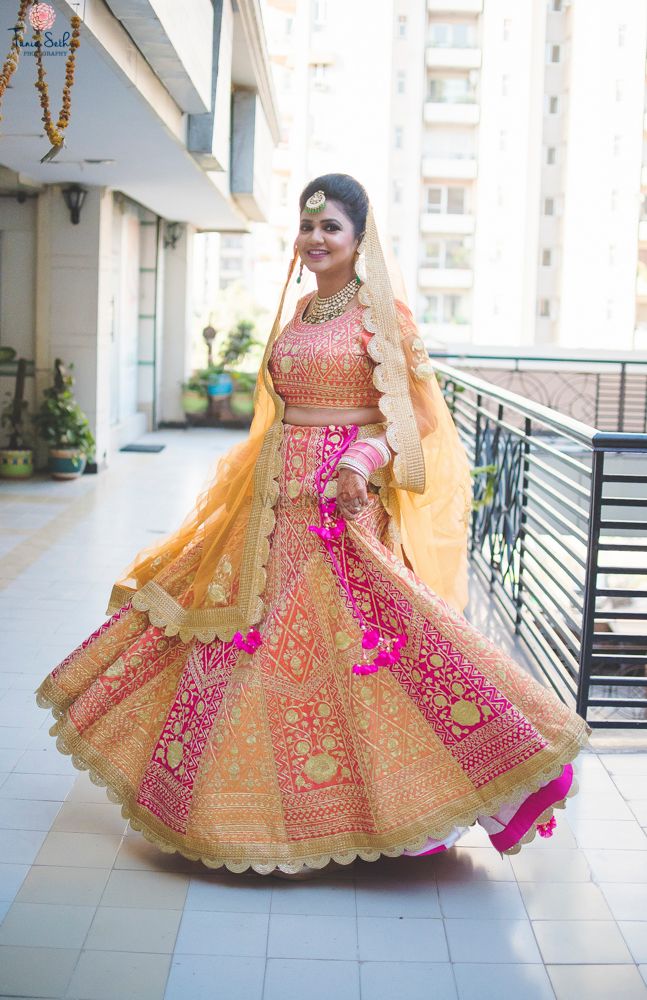 Photo of Bride twirling in peach and coral lehenga