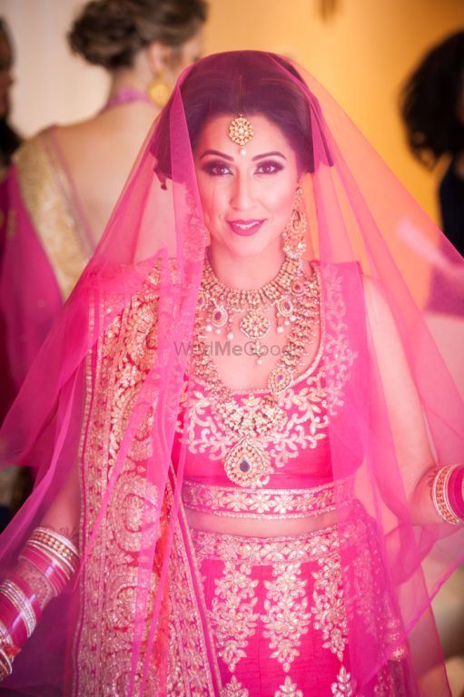 Photo of Bride in bright pink lehenga with dupatta as veil
