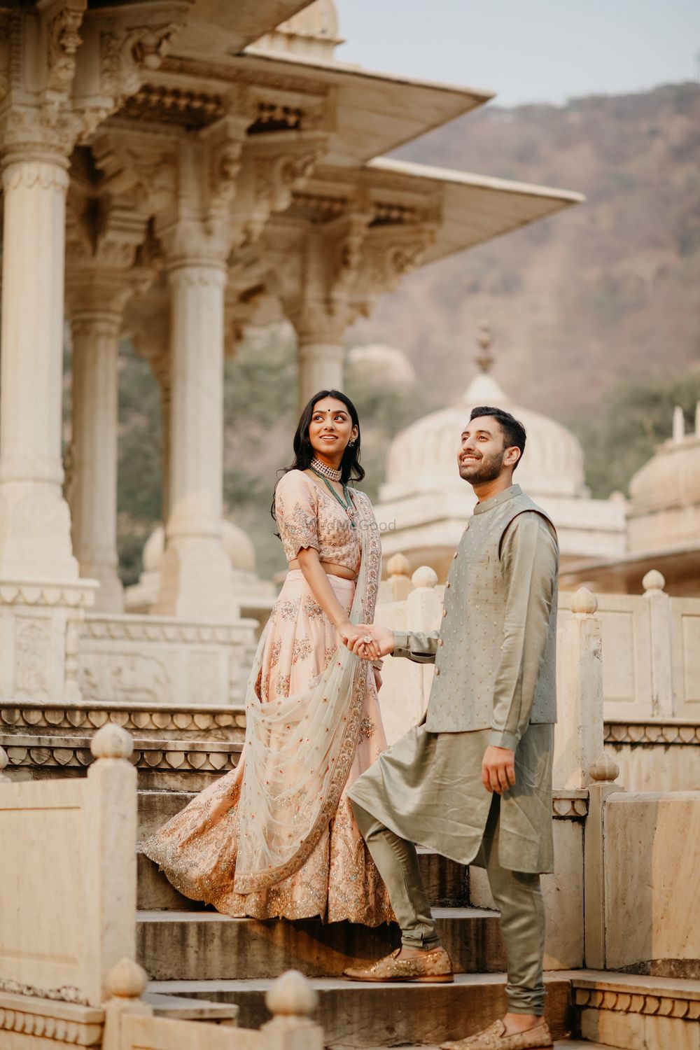 Photo of Bride and groom posing against a royal palace.