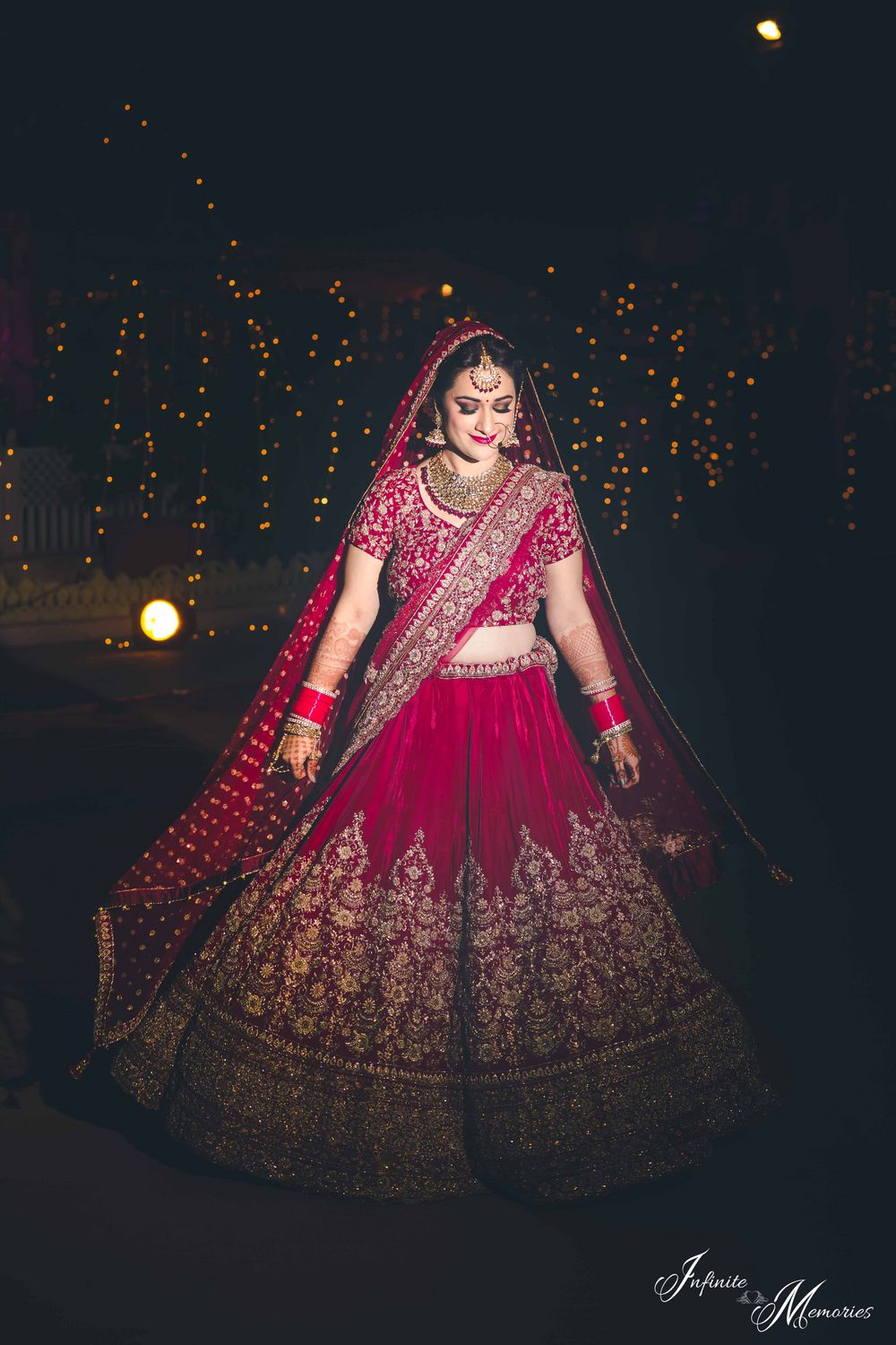 Photo of Bride posing in deep red bridal lehenga at night