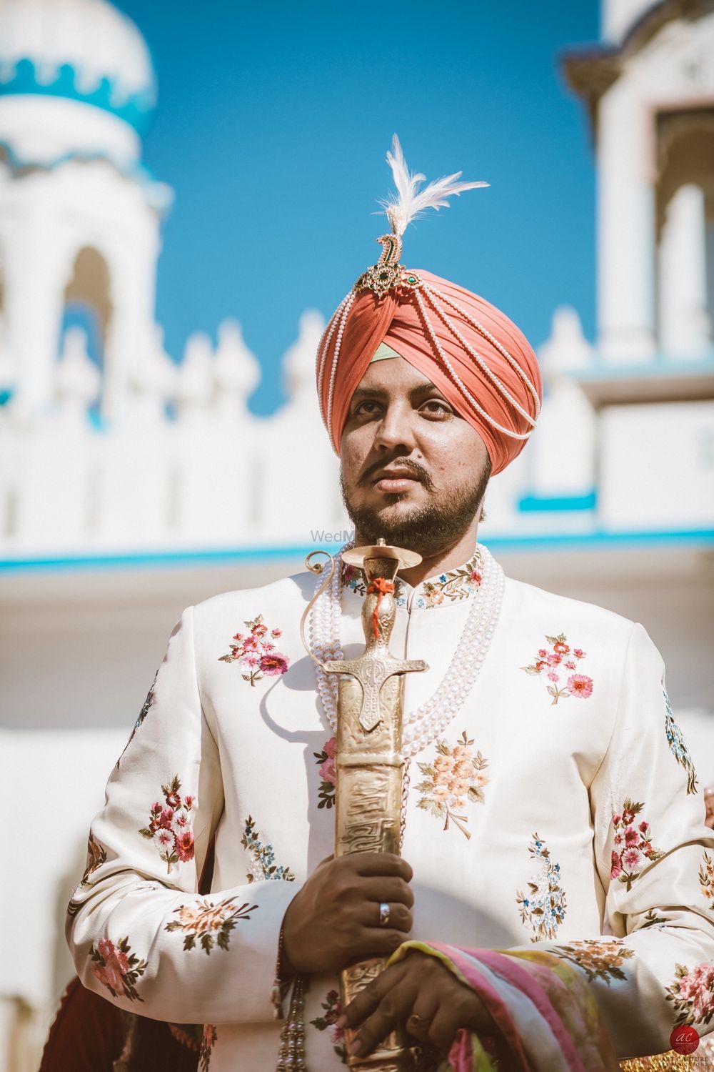 Photo of Sikh groom in floral sherwani and orange pagdi