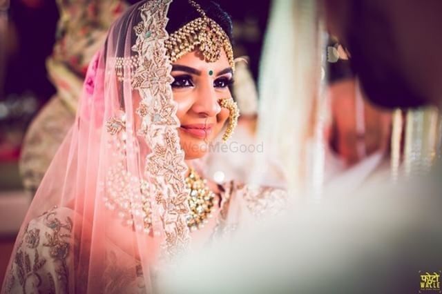 Photo of A bride in light pink lehenga and golden jewelry