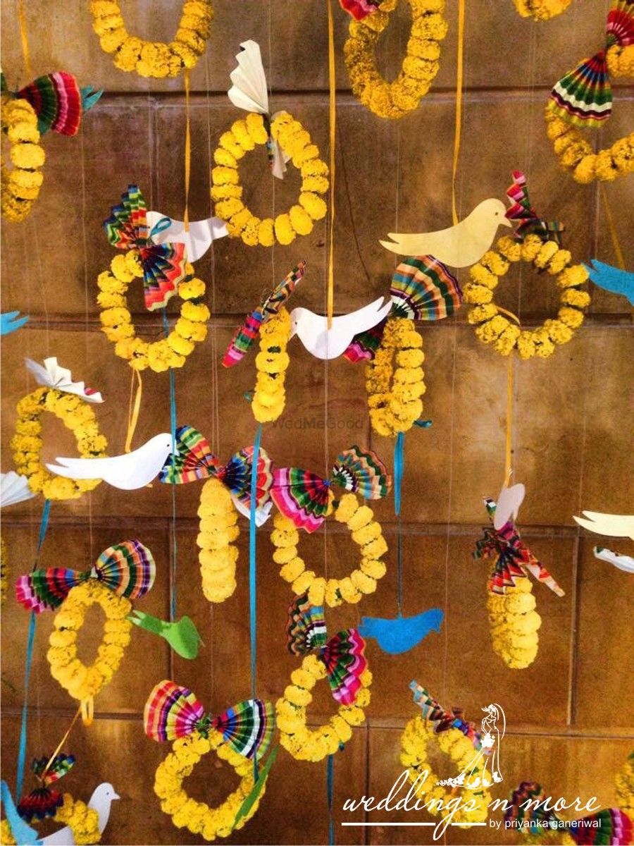 Photo of Mehendi decor idea with hanging genda phool rings and bird cutouts