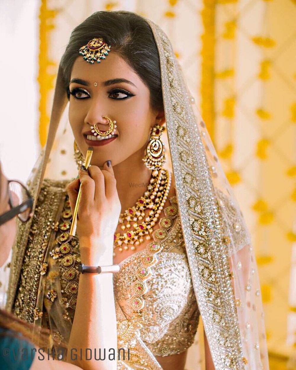 Photo of Bride getting ready wearing off white and gold lehenga