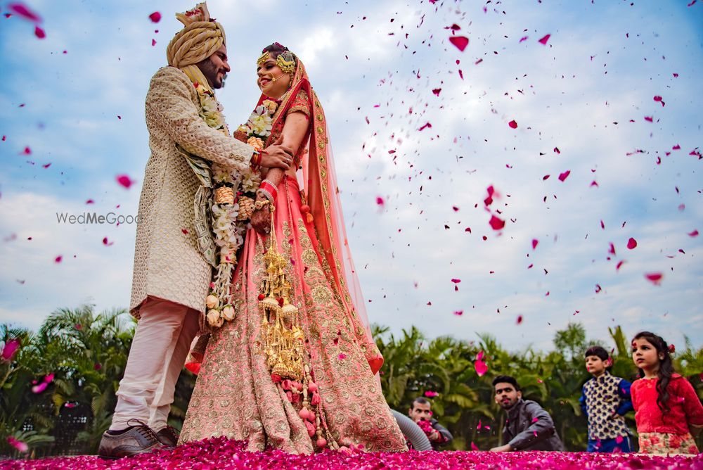 Photo of Couple portrait with guests throwing rose petals