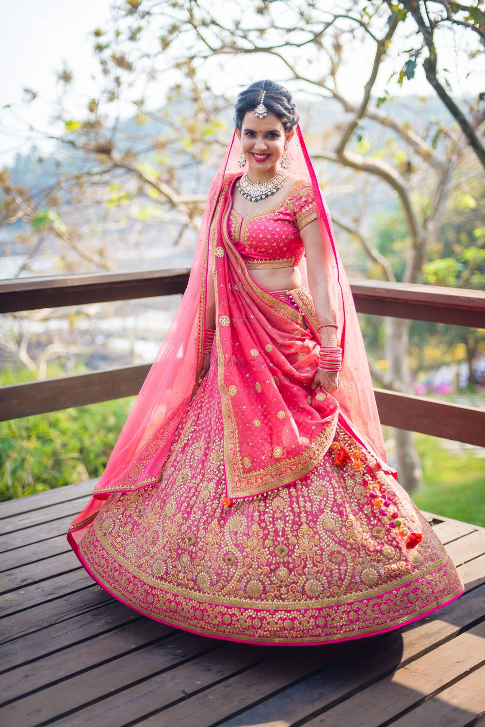 Photo of Bride twirling in coral lehenga with gold embroidery