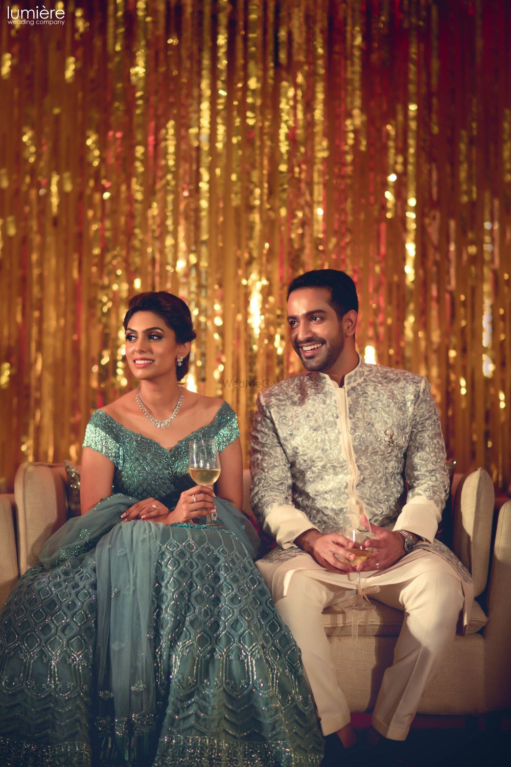 Photo of Bride and groom on engagement with gold string backdrop
