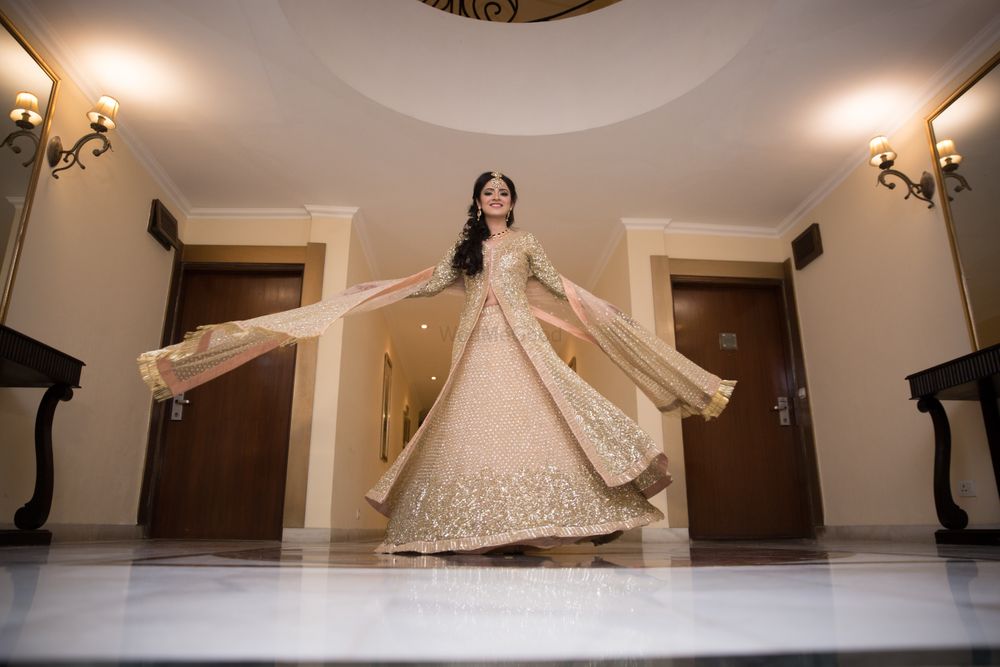 Photo of Bride twirling in gold lehenga with sequin work