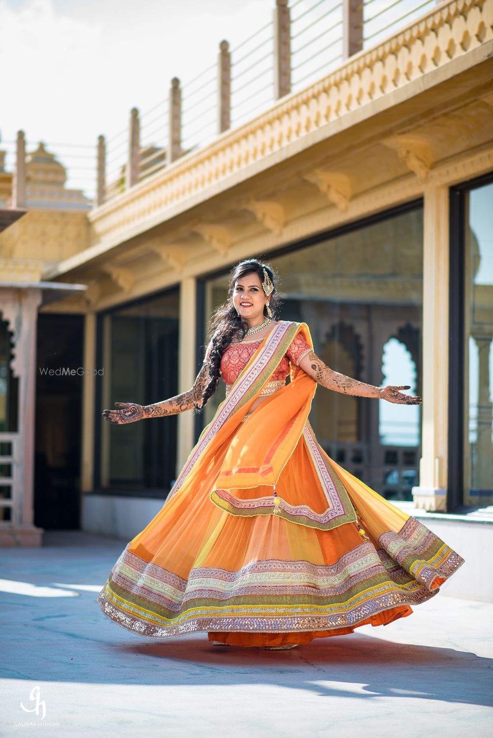 Photo of Bride twirling in orange and yellow lehenga