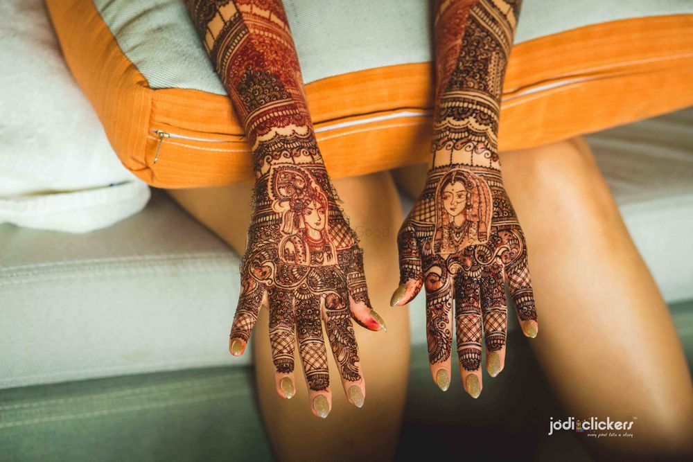 Photo of Mehendi with portraits of bride and groom on back of hands