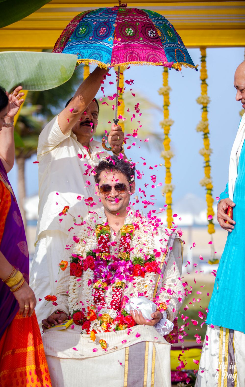 Photo of Groom entry with falling petals and umbrella