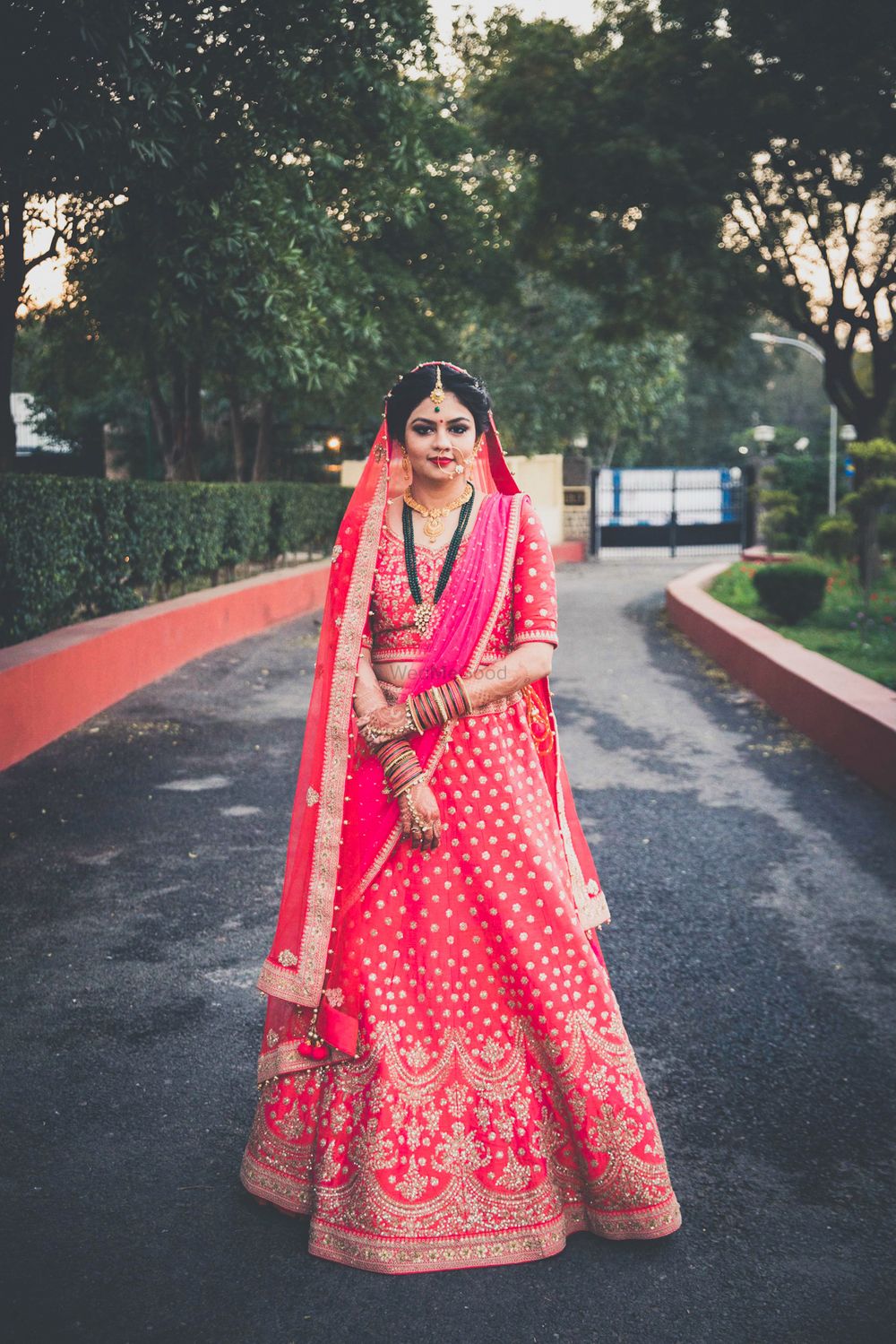 Photo of Red and gold bridal lehenga with long green necklace
