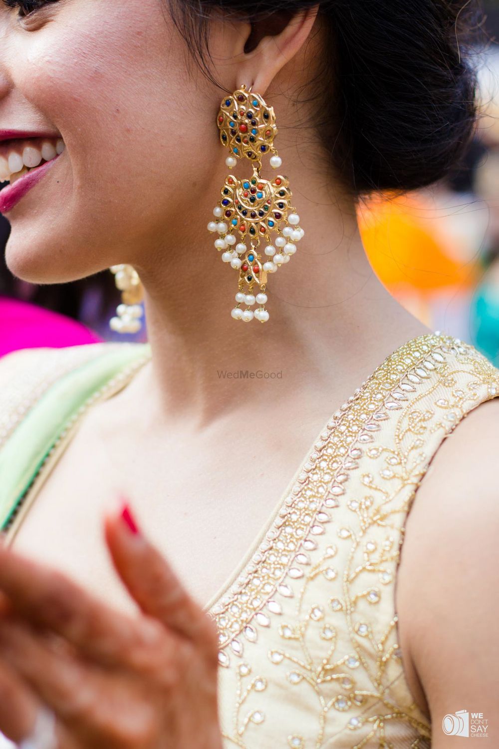 Photo of Bride wearing colourful earrings for mehendi with pearls