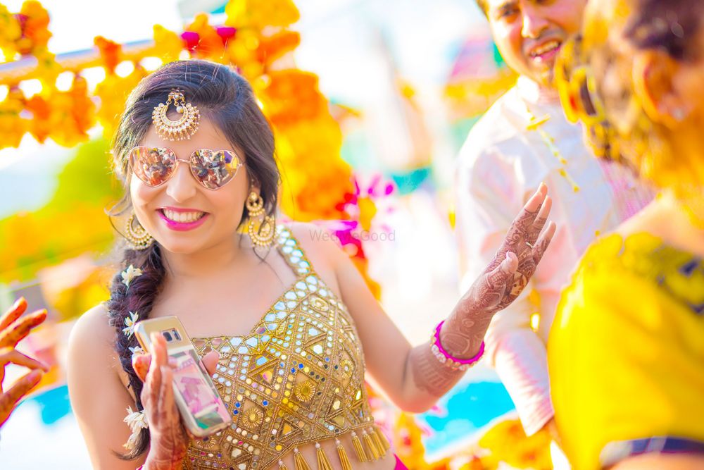 Photo of Bride on mehendi wearing mirror work blouse and sunglasses