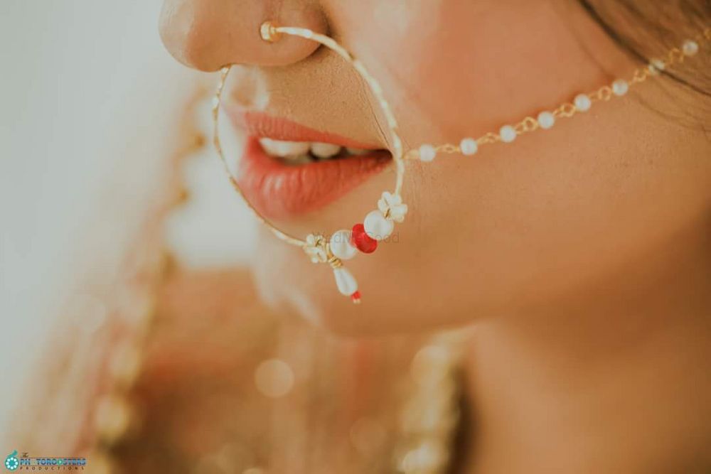 Photo of A bride in a nath with red and white beads.