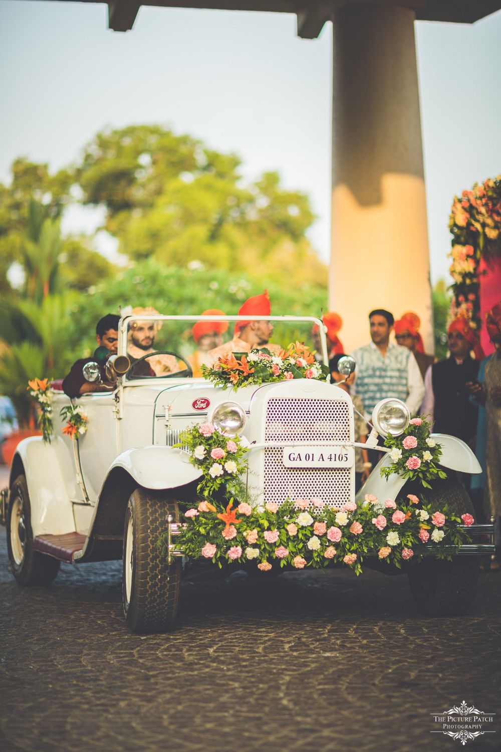 Photo of Groom entering his wedding in a vintage car