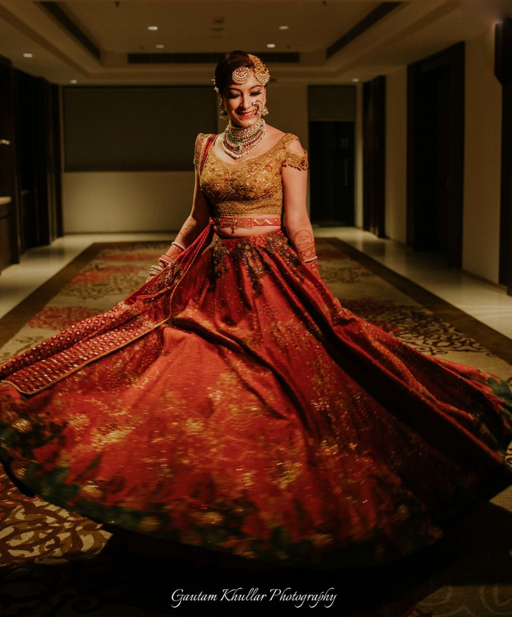 Photo of Gold and red lehenga twirling bride