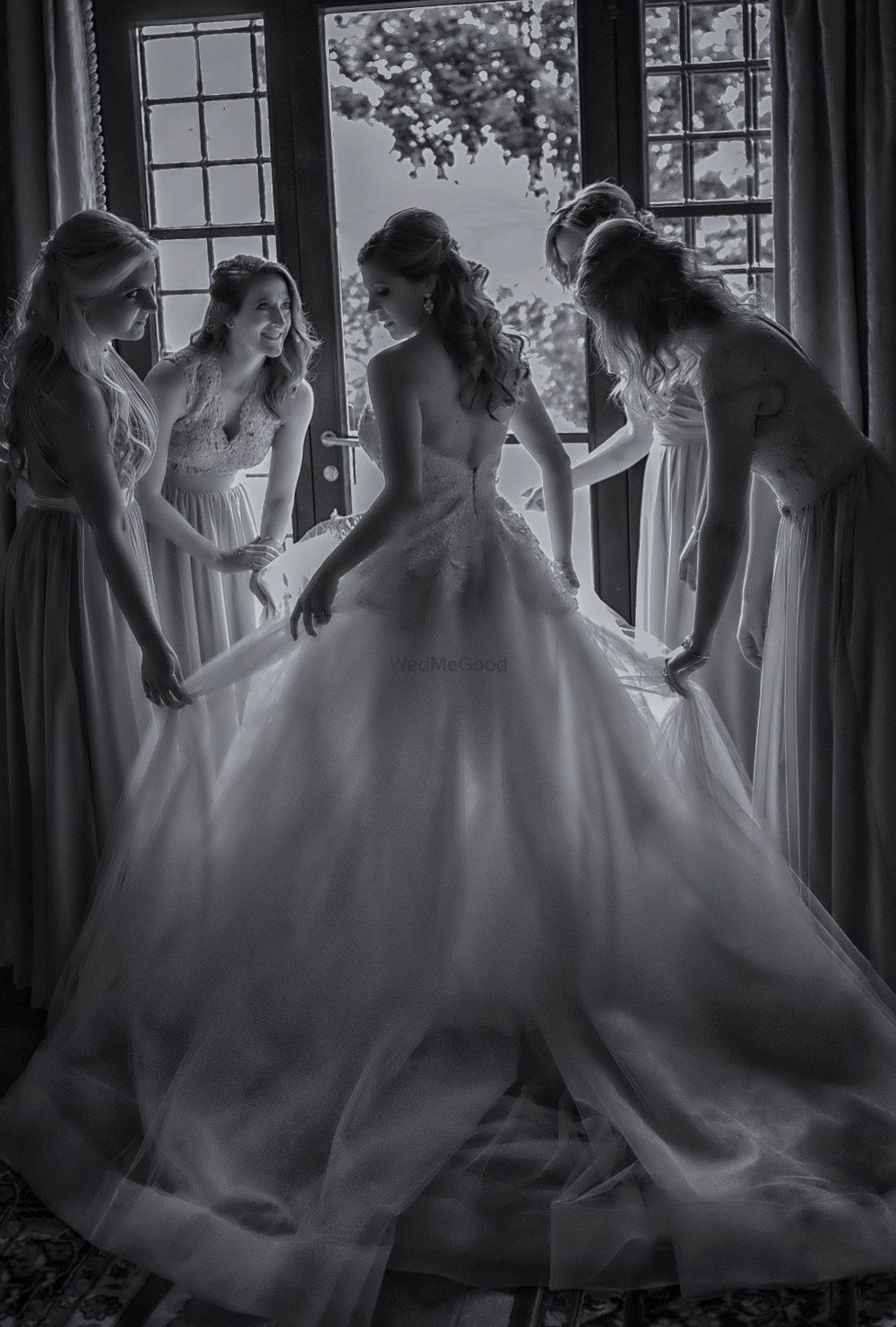 Photo of Bridesmaids help a Christian bride with her wedding gown