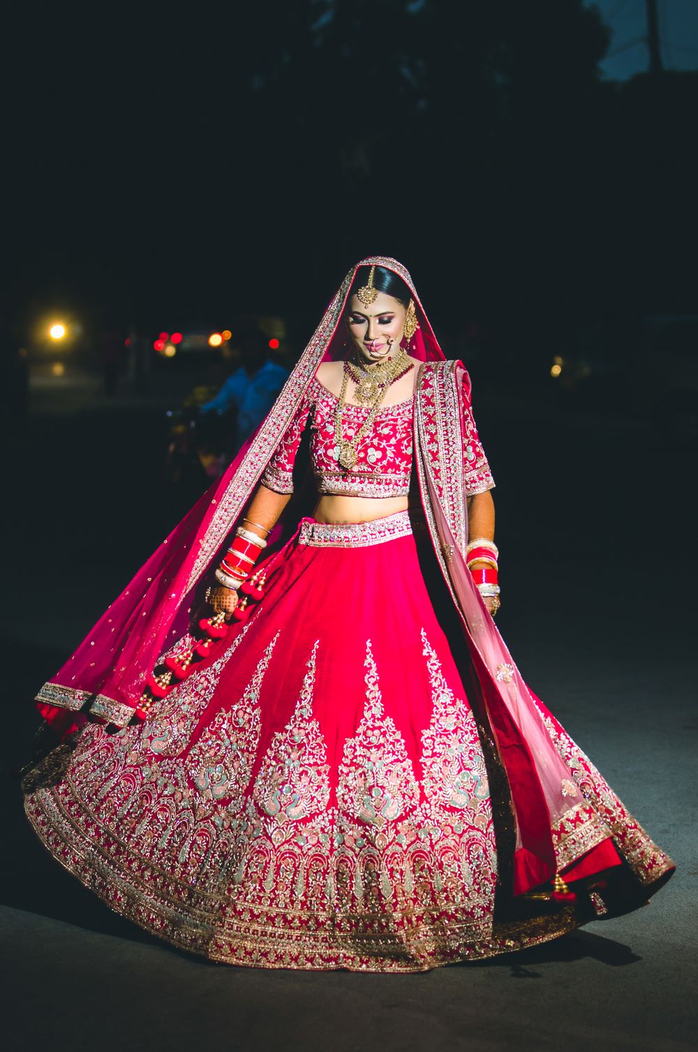 Photo of Bride showing off red and gold bridal lehenga