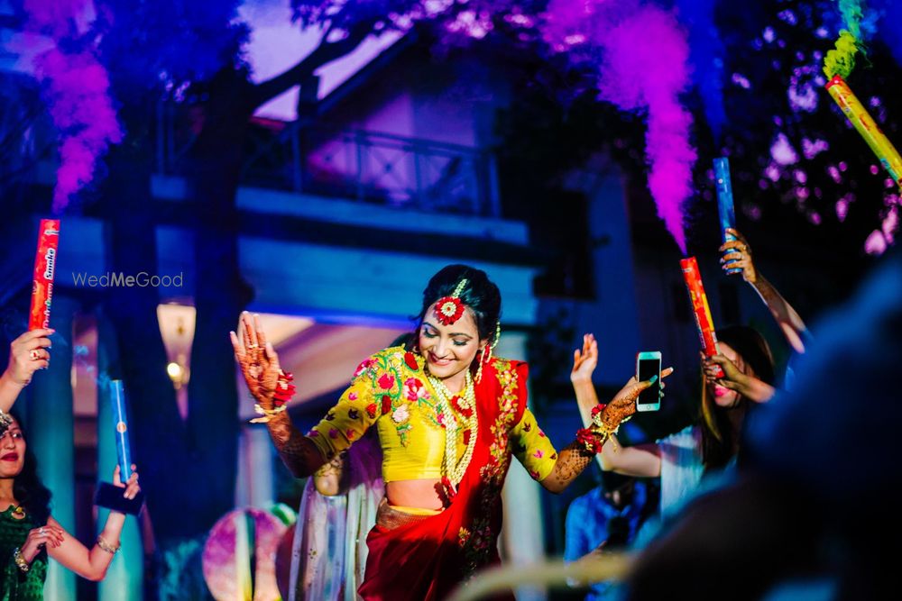 Photo of Bride entering on mehendi with guests holding smoke sticks