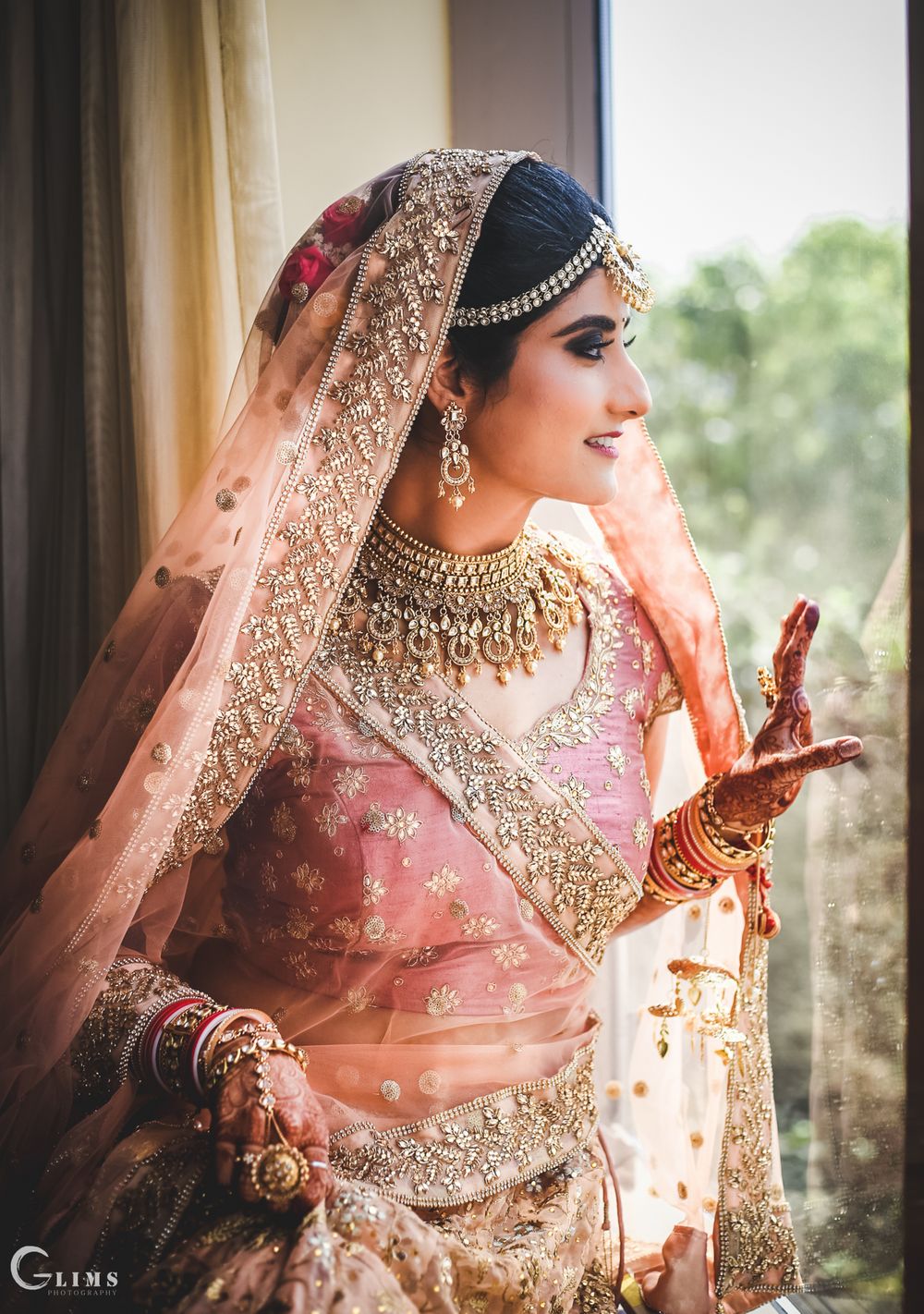 Photo of Bride by the window in a dusty peach lehenga