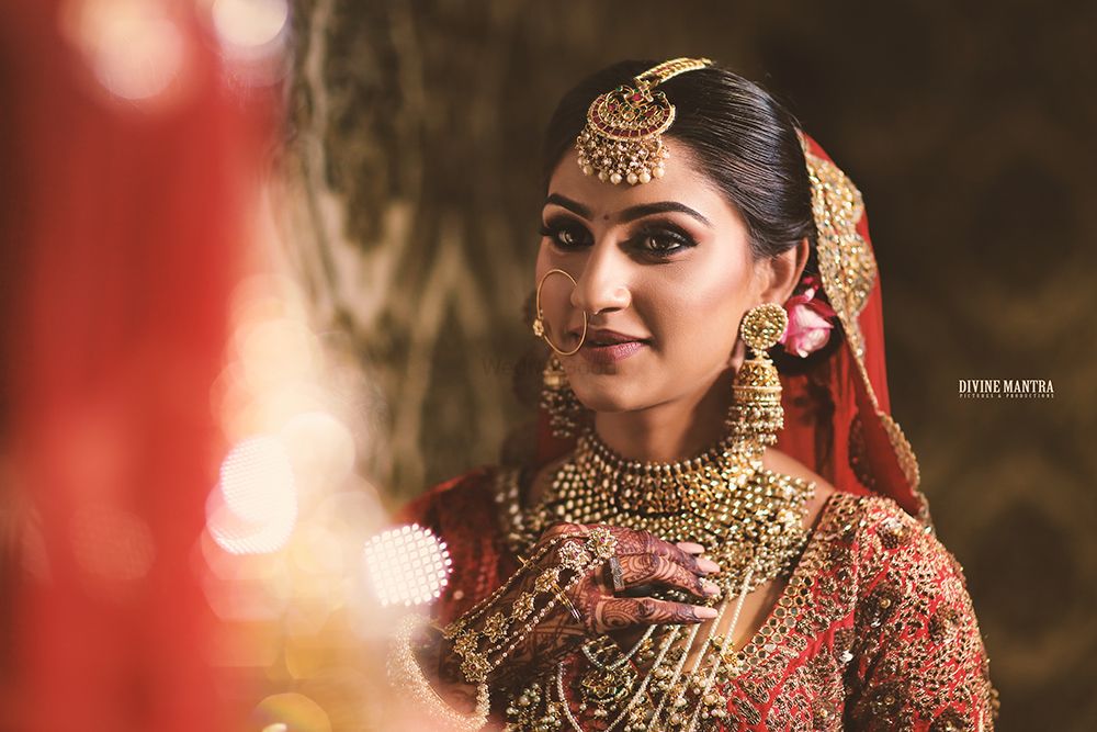 Photo of Bride looking into mirror with heavy bridal jewellery