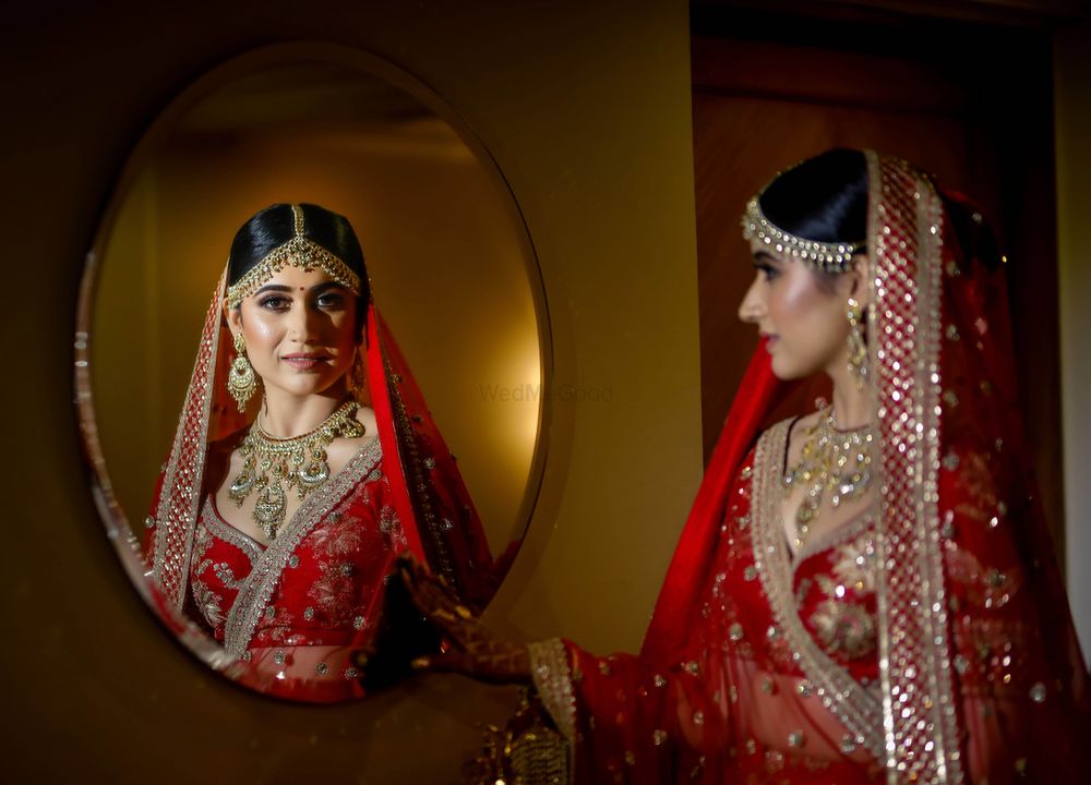 Photo of Bride looking in mirror in red lehenga