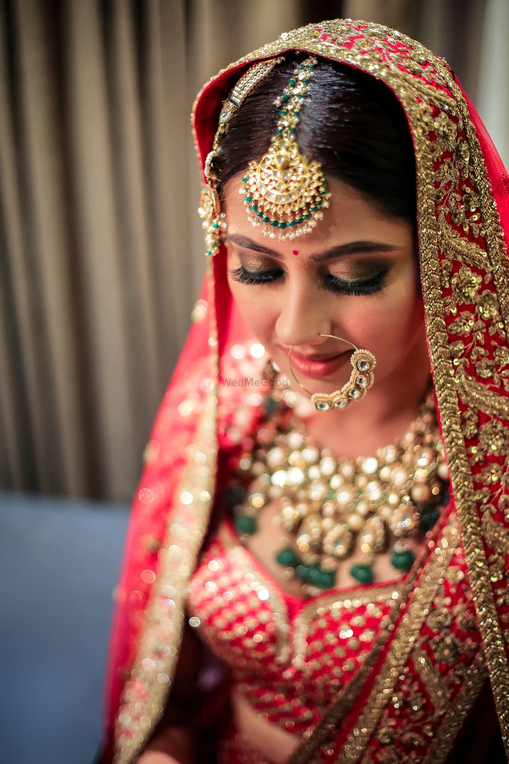 Photo of Bride in red lehenga contrasting jewellery