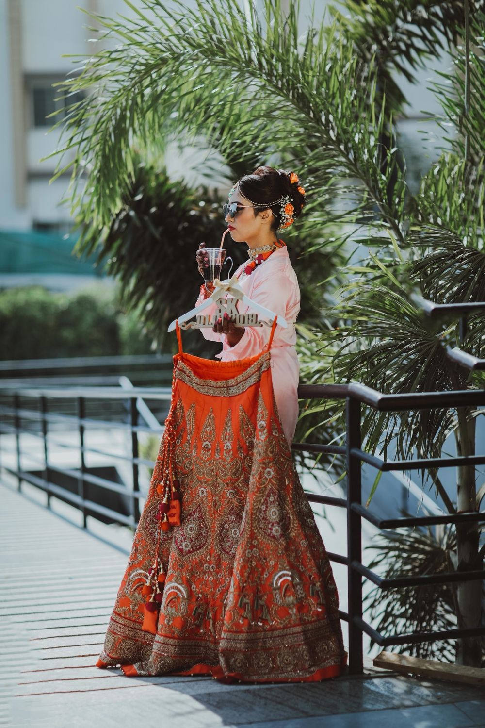 Photo of Bride holding lehenga and having a drink