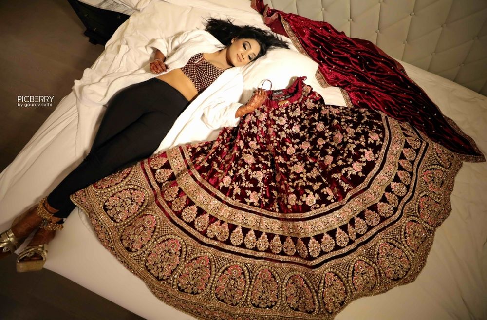 Photo of Bride on bed with maroon bridal lehenga