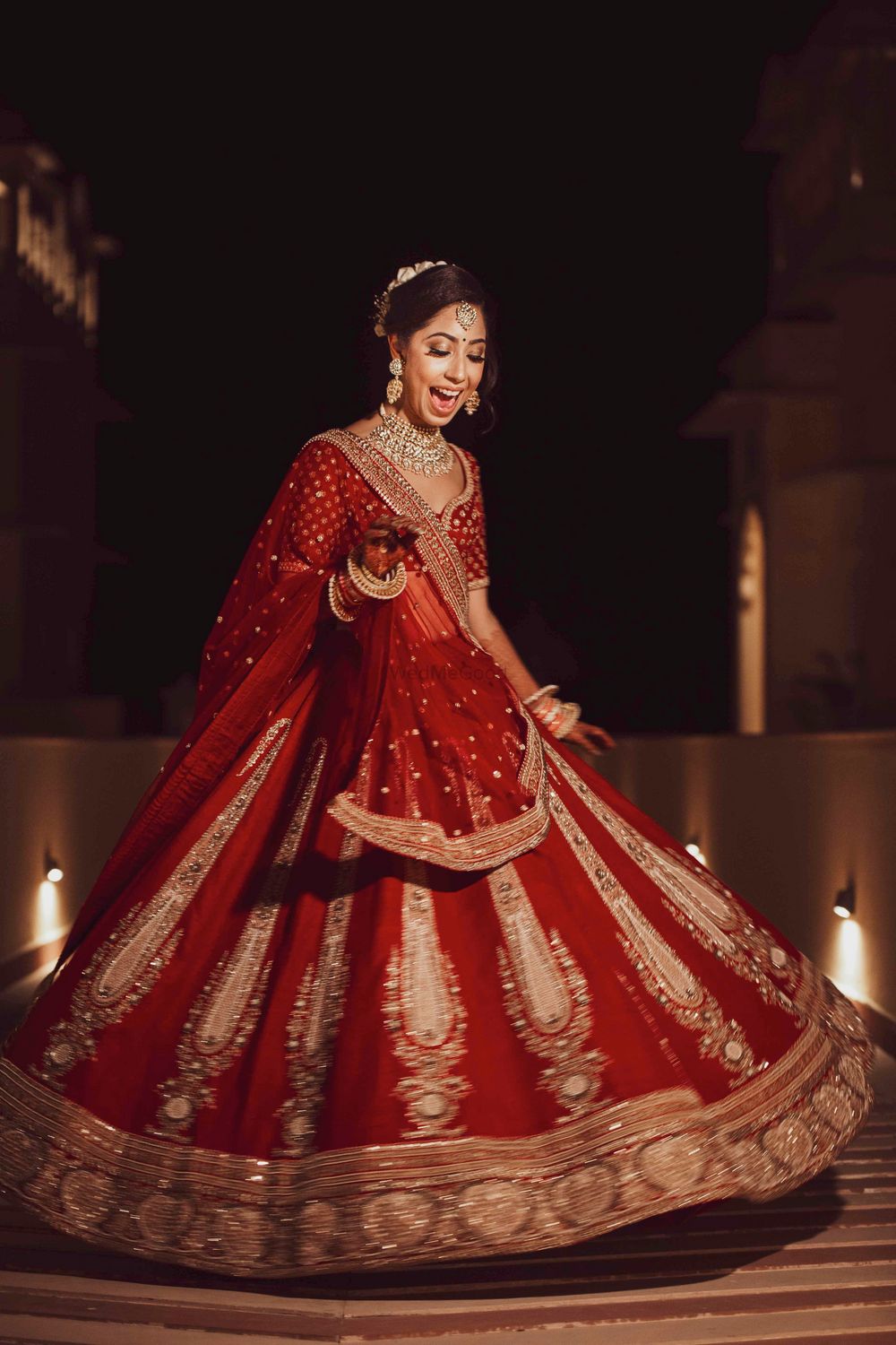 Photo of Bride twirling in red and gold simple lehenga