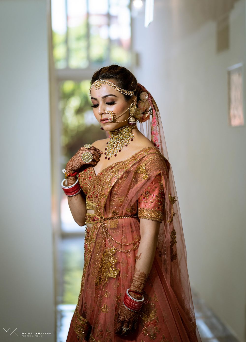 Photo of A beautiful bride in a stunning peach lehenga with marvellous gold jewellery.