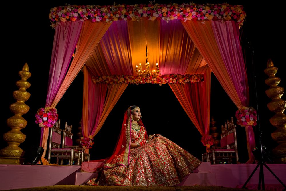 Photo of Bride in red posing against the mandap