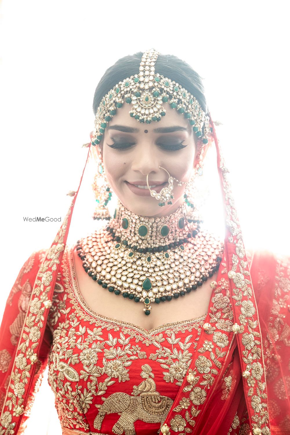 Photo of Contrasting green jewellery with red lehenga for north indian bride