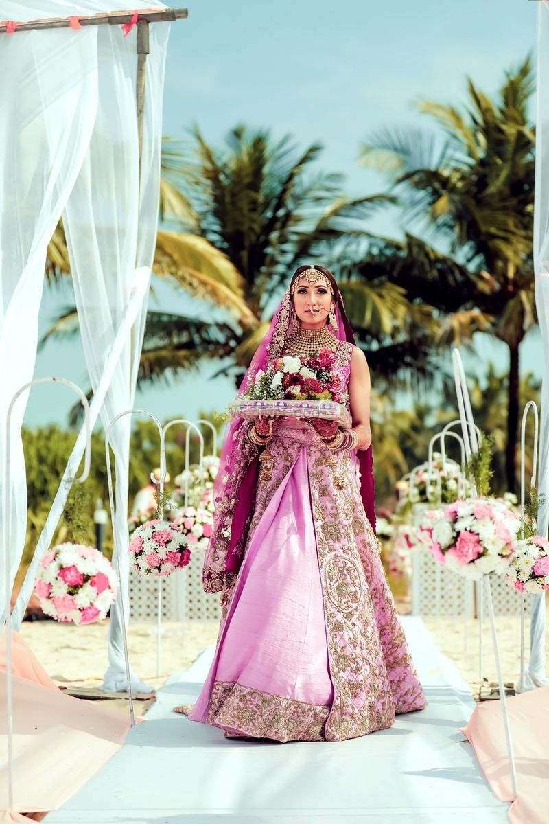 Photo of Bridal entry in light pink lehenga holding bouquet