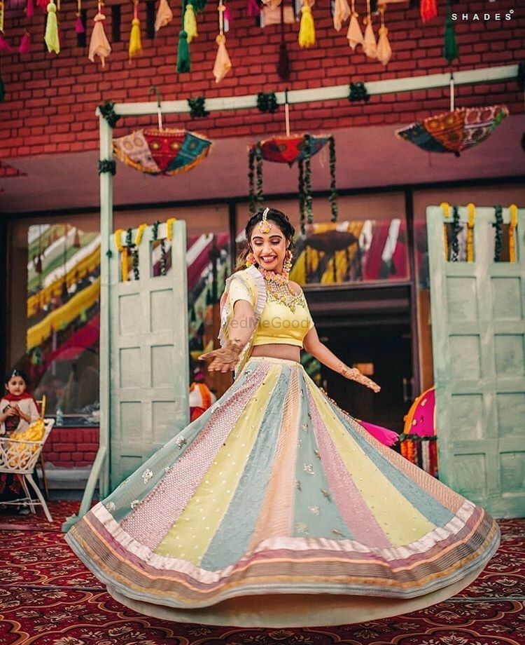 Photo of A bride in a pastel patchwork lehenga twirling on her mehendi day
