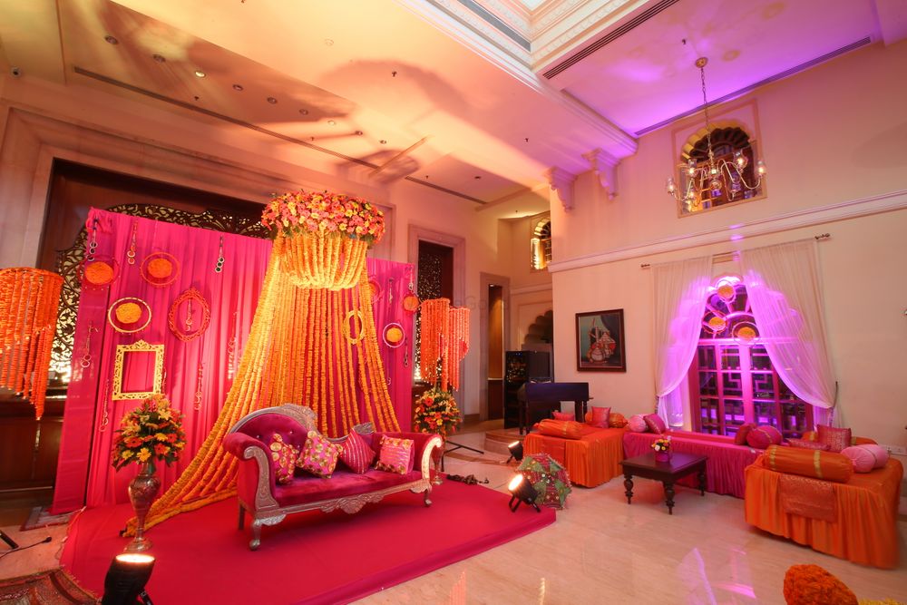 Photo of Mehendi sangeet stage decor with pink backdrop and marigolds