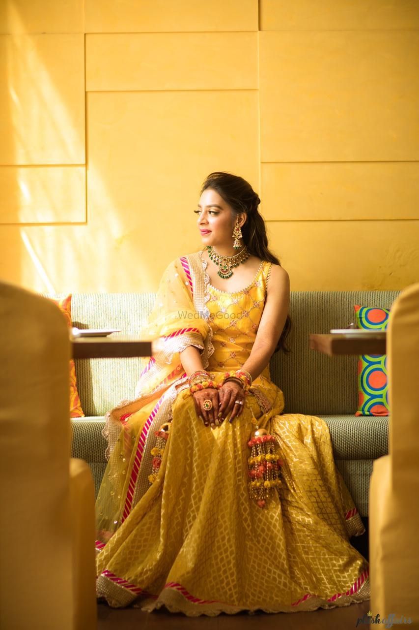 Photo of A bride in a yellow outfit and pompom kaleere for her mehndi